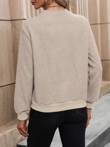 Vue détaillée d'un sweat beige texturé avec motif en losanges et finitions côtelées