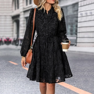 Detailed view of the black textured fabric and tiered ruffle hem of this vintage dress