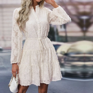 Detail of white lace dress featuring intricate fringe jacquard texture and tiered skirt