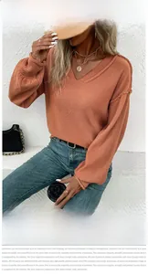 Détail de pull en maille à col en V avec bords effilochés et des manches lanternes