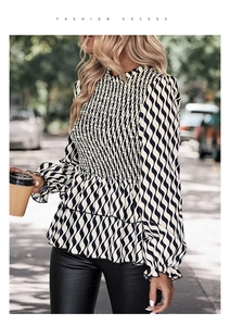 Detailed view of the smocked chest and ruffled hem on black and white striped top