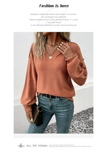 Détail d'un pull en tricot à col en V rouge brique avec poignets côtelés et tissu doux