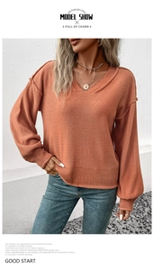 Vue détaillée du pull en maille rouge brique avec col en V et manches lanternes