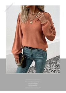 Détail du col en V et des manches lanternes d'un pull en maille de couleur orange brique