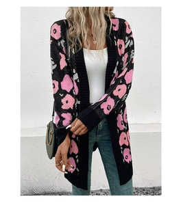 Détail d'un cardigan en maille douce avec motifs floraux roses sur tissu noir