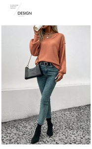 Détail d'un pull en maille col V rouge brique avec coutures apparentes et manches
