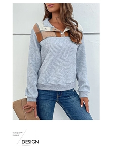 Close-up of women's grey quilted pullover featuring brown plaid patchwork and snap collar