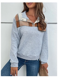 Detail of grey quilted sweatshirt with vintage plaid collar and metal snap buttons