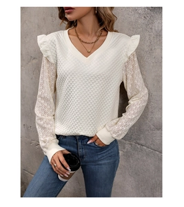 Close-up of V-neck top with ruffled shoulders, quilted texture, and sheer lace sleeves