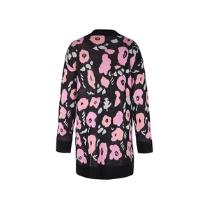 Détail de pull en maille avec fleurs roses et poignets côtelés noirs sur les manches