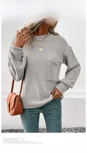 Detail of light grey knit sweater featuring a raw-edge chest pocket and ribbed cuffs