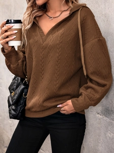 Detail of dark brown knit hoodie featuring textured diamond weave and V-neck drawstring