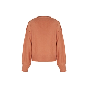 Détail d'un pull en maille orange brique avec coutures apparentes et poignets côtelés