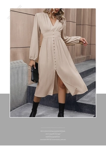 Dettaglio di un abito midi beige con scollo a V, cintura e bottoni davanti alle scale