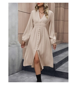 Dettaglio dell'abito beige a pieghe con profondo scollo a V e spacco frontale con bottoni