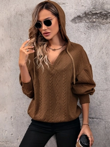 Close-up of textured knit hoodie showing cable pattern and drawstring details in brown