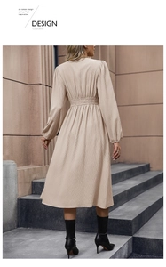 Dettaglio dell'abito beige a pieghe con maniche lunghe, vita elastica e drappeggio