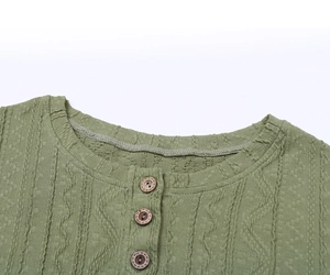 Détail du haut en tricot vert sauge avec col rond Henley et trois boutons en bois marron