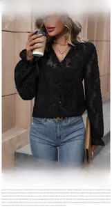 Detail of black semi-sheer lace blouse with floral texture and ruffled cuffs