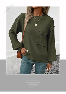 Detail of dark green loose knit sweater with drop shoulder and contrast stitching