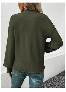 Detail of loose fit dark green knitted sweater showing textured fabric and ribbed cuffs