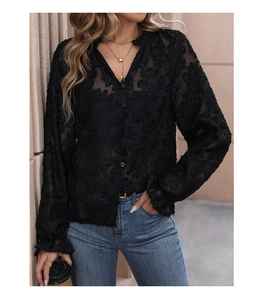 Detail of black semi-transparent shirt showing 3D floral texture and ruffle cuffs