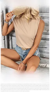 Detail of beige sleeveless pleated top paired with distressed denim shorts