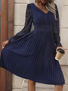 Détail d'une robe plissée bleu marine avec col en V et manches en dentelle élégante