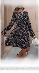 Detail of black floral mini dress with pink blossoms, ruffled cuffs and tied waistline