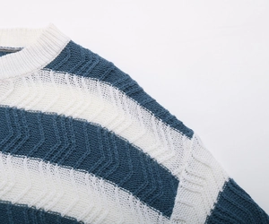 Detail of the navy blue and white wavy knit texture and ribbed crew neck on the sweater