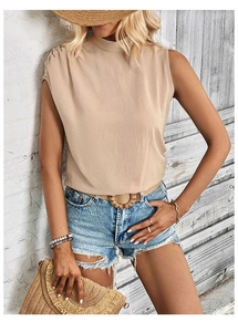 Detail of apricot sleeveless top featuring a mock neck and pleated shoulder texture