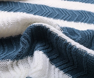 Detailed texture of blue and white striped knit fabric with herringbone and cable patterns