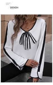 Detail of V-neck white blouse featuring contrast bow tie and black striped long sleeves