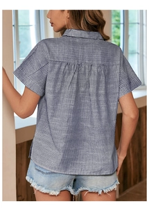 Détail d'une chemise à manches courtes rayée bleu et blanc avec pli plat dans le dos