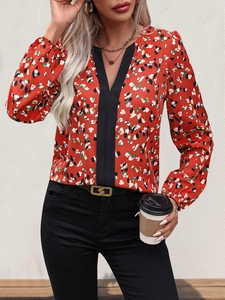 Detail shot of a women's V-neck floral blouse featuring contrast black trim and red patterns