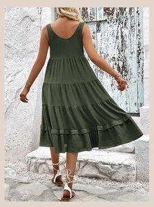 Back view of a tiered dark green sleeveless midi dress against a rustic stone background