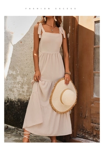 Detail of beige tiered summer dress with bow shoulder straps and textured fabric