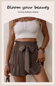 Detail of high waist brown shorts with a decorative bow and white lace corset top
