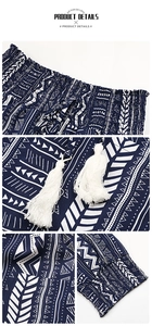 Detail view of ethnic print pants showing elastic waistband with white cotton tassels