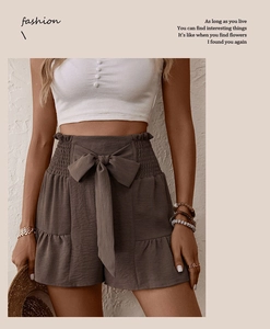 Detail of high waisted brown shorts with large bow tie belt and ruffled hem texture