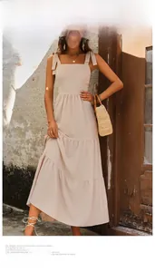 Detail of beige sleeveless maxi dress with adjustable bow straps and tiered skirt