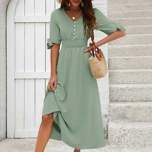 Detail of elegant V-neck green midi dress with bow-tie sleeves and button accents