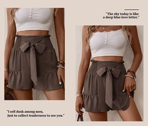 Detail of high-waisted summer shorts with elastic ruffled waist and large ribbon tie