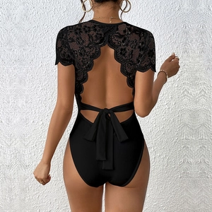 Détail du dos d'un body noir avec dentelle florale et un grand nœud sur le design dos nu