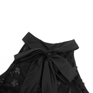 Détail de robe en organza noir avec appliques florales 3D et décolleté licou à nœud