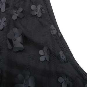 Détail de fleurs 3D en organza noir avec perles centrales sur un tissu en maille