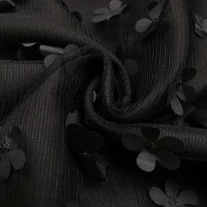 Détail d'appliqués floraux 3D et de perles sur le tissu en organza noir de la robe