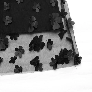 Vue détaillée des appliques florales 3D sur le tissu en maille organza noir de la robe