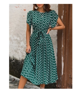 Détail d'une robe plissée vert foncé avec motifs floraux blancs et ceinture à la taille