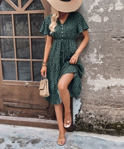 Detailed view of dark green polka dot dress with V-neck, buttons and ruffled layers